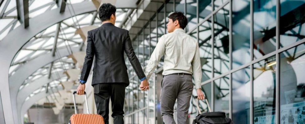 Gay businessmen holding hands walking at airport